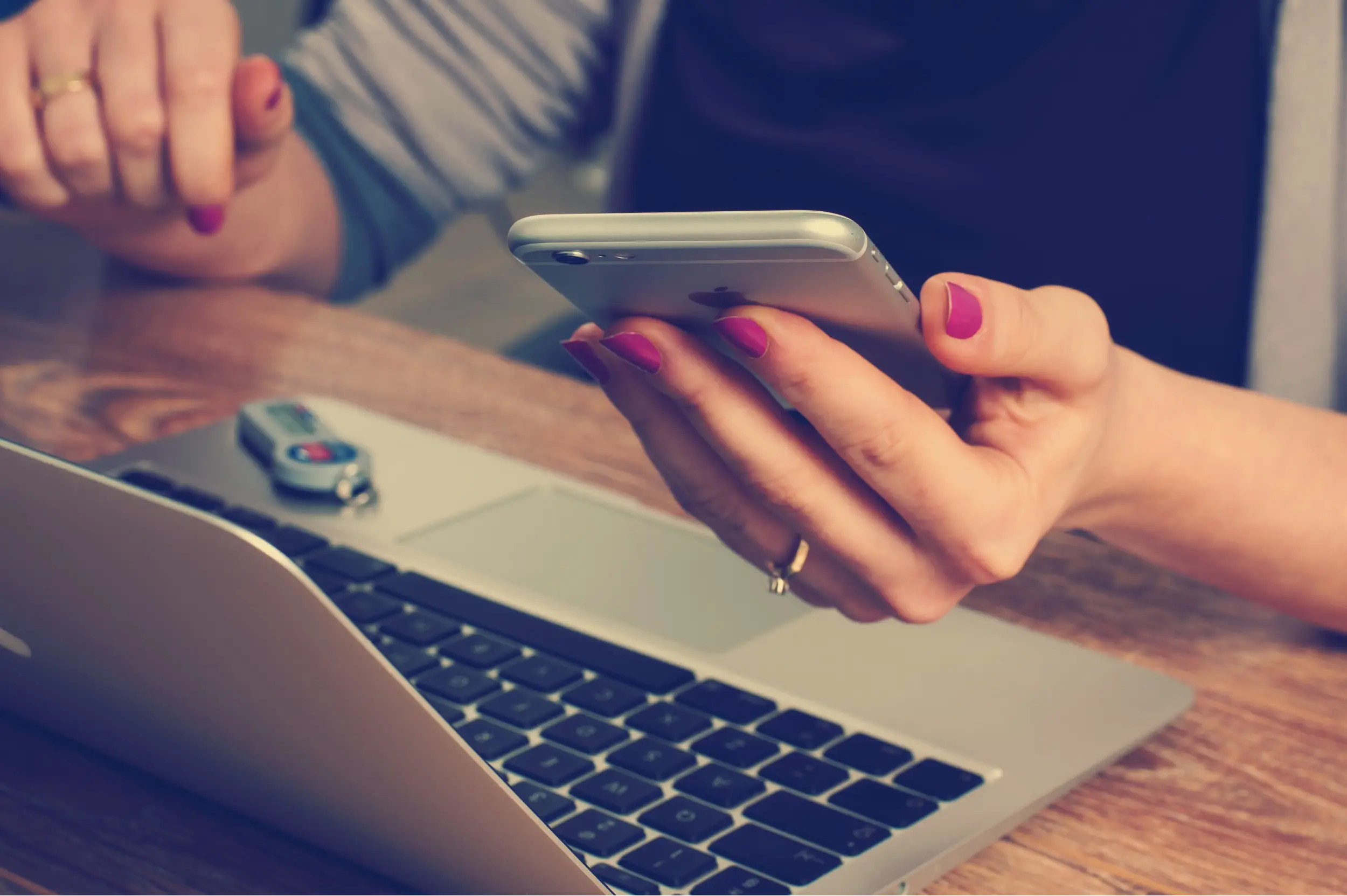 User checking a business application on a smartphone next to their laptop